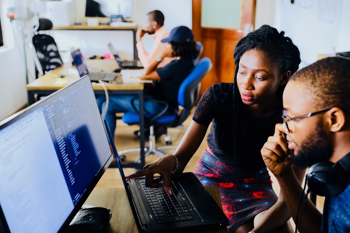 two adults sitting by a computer